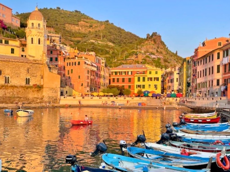 Vernazza harbor at sunset with colorful buildings reflected in the calm water of Cinque Terre
