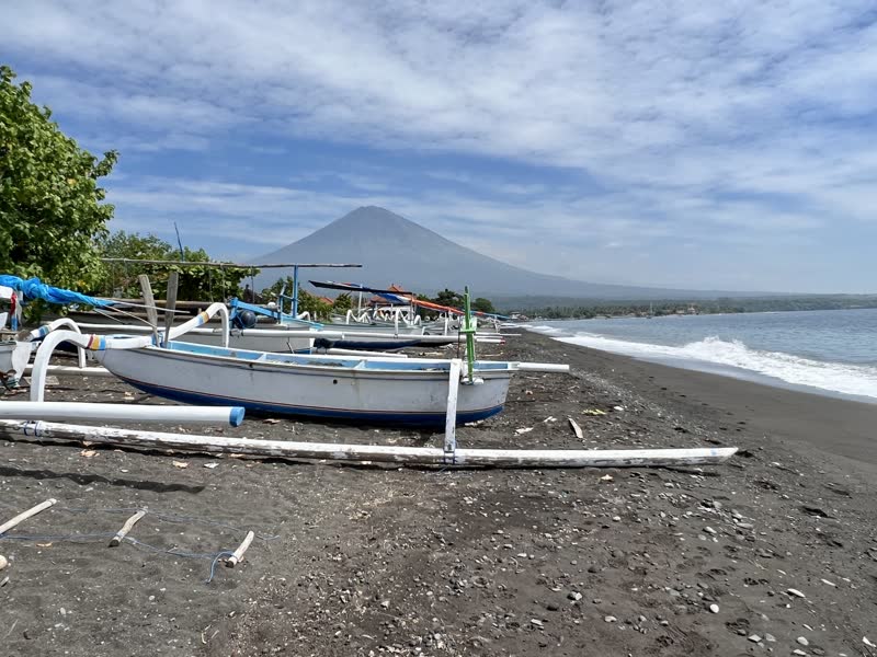 Jemeluk Bay in Amed, Bali — traditional jukung fishing boats on black sand beach with Mount Agung in the background