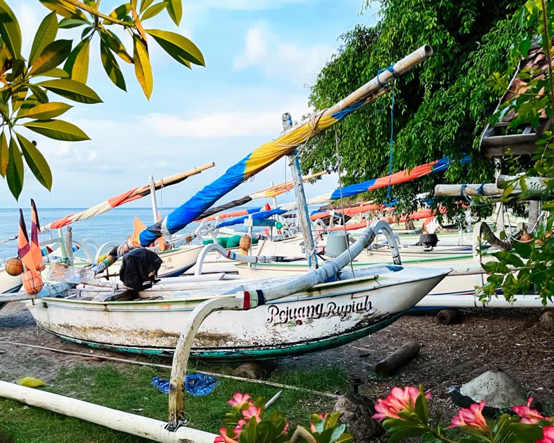 Aerial view of Amed Beach with traditional fishing boats on black sand and turquoise water