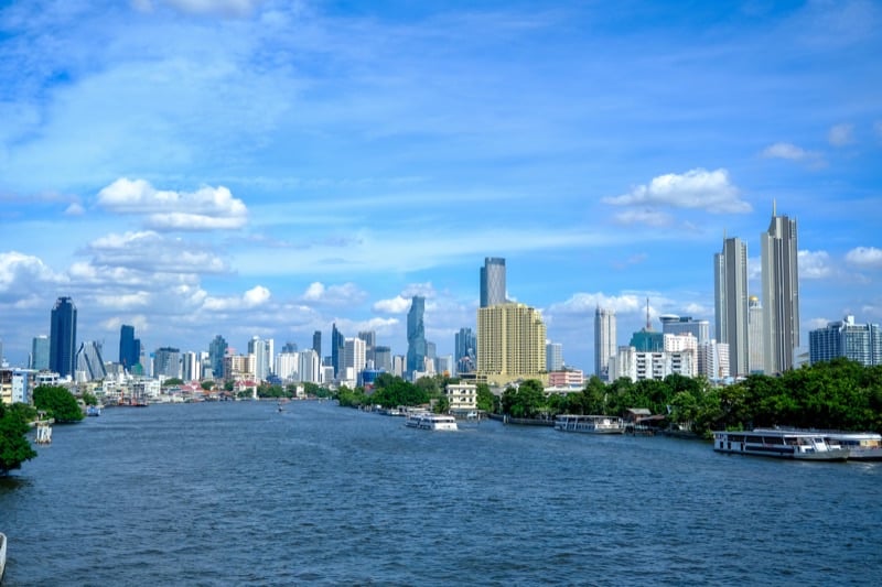Bangkok skyline and Chao Phraya River at sunrise — the golden spires of Wat Arun visible in the distance