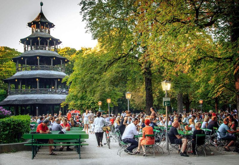 Munich's English Garden beer garden — locals and tourists alike drink in the sun alongside the Eisbach river