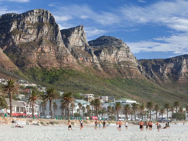Camps Bay beach in Cape Town with the Twelve Apostles mountains as a backdrop and crystal-clear Atlantic water