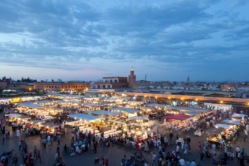 Jemaa el-Fna square in Marrakech buzzing with food stalls, musicians, and storytellers at dusk