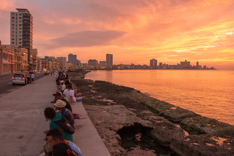 Havana's iconic Malecón seafront boulevard at sunset with pastel colonial buildings