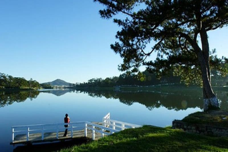 Xuan Huong Lake Da Lat Vietnam with reflections of pine trees and mountains in the still water