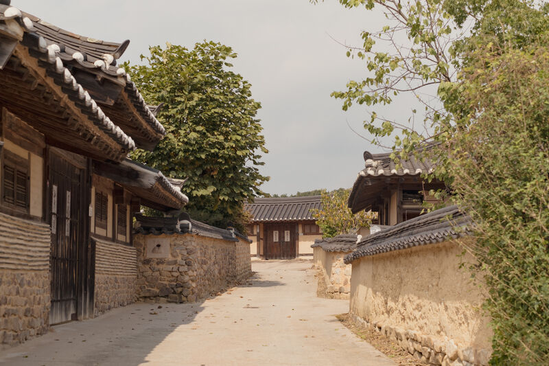Traditional thatched-roof path winding through Andong Hahoe Folk Village with ancient hanok homes on either side