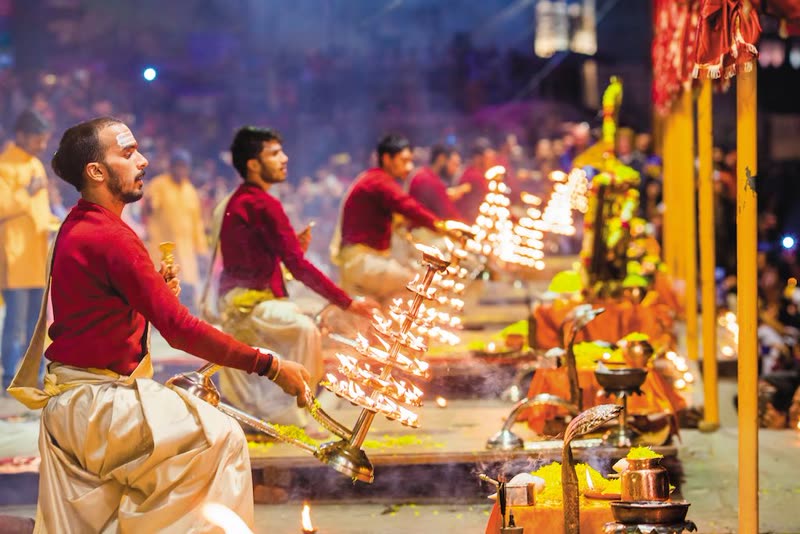 Evening Ganga Aarti at Dashashwamedh Ghat in Varanasi — priests performing synchronized fire rituals with brass lamps and incense along the Ganges river at dusk