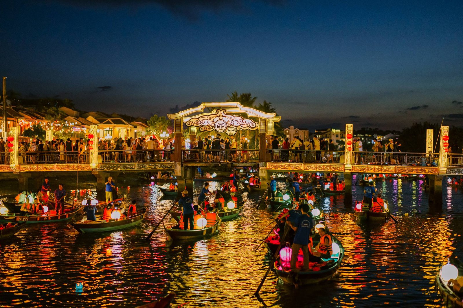 Hoi An Ancient Town at night — colored paper lanterns strung across alleys reflected on the Thu Bon River