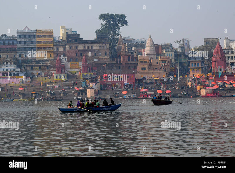 The sacred Ganges River ghats at Varanasi, India — ancient stone steps descending to the holy river at dawn with cremation pyres and pilgrims
