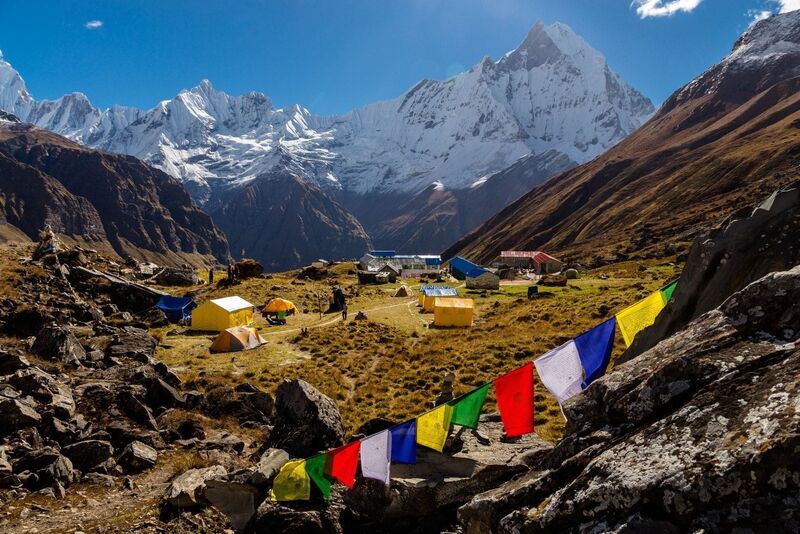 The Annapurna mountain range in Nepal — dramatic Himalayan peaks towering above terraced hillside trails under a clear blue sky