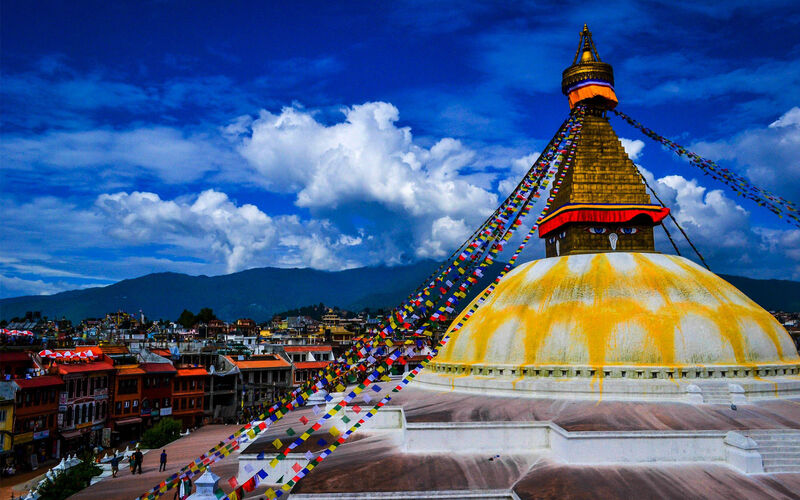 Boudhanath Stupa in Kathmandu, Nepal — the world's largest stupa with the characteristic Buddha eyes painted on the tower, surrounded by prayer flags and Buddhist pilgrims