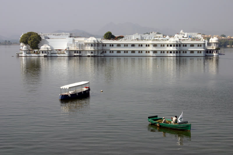 Lake Palace hotel in Udaipur floating on Lake Pichola — the iconic white marble palace rising from the water with the Aravalli hills in the background at dusk