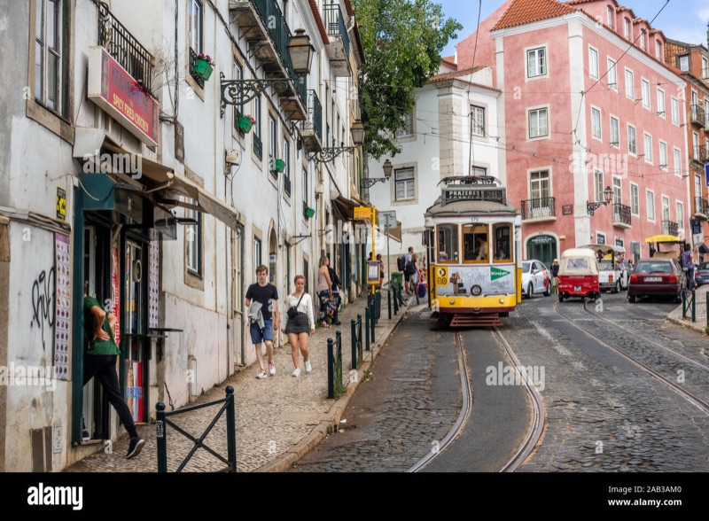 The iconic yellow Tram 28 at Miradouro de Santa Luzia in Lisbon's historic Alfama district