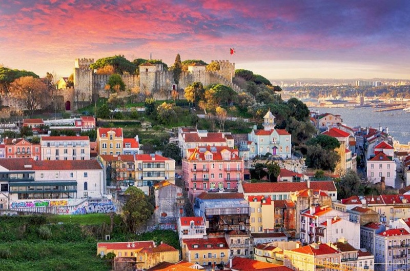 Lisbon's Alfama district skyline with São Jorge Castle rising above the terracotta rooftops at golden hour