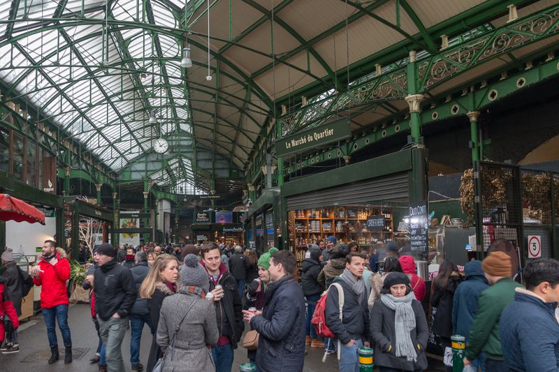 Bustling Borough Market in London with vendors and shoppers browsing fresh food stalls