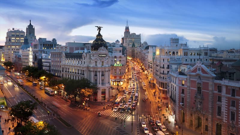 Madrid's Gran Vía boulevard at dusk, illuminated buildings and the iconic Metropolis building