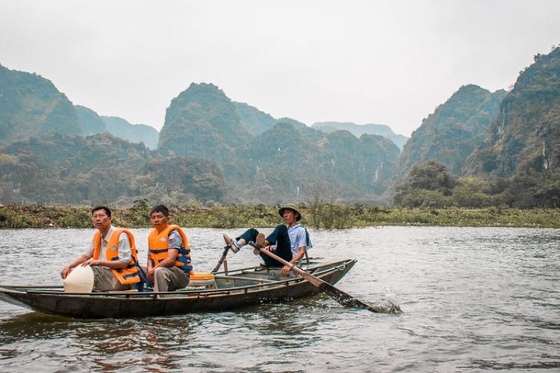 Traditional rowboat navigating the Tam Coc river through limestone karst scenery in Ninh Binh, northern Vietnam