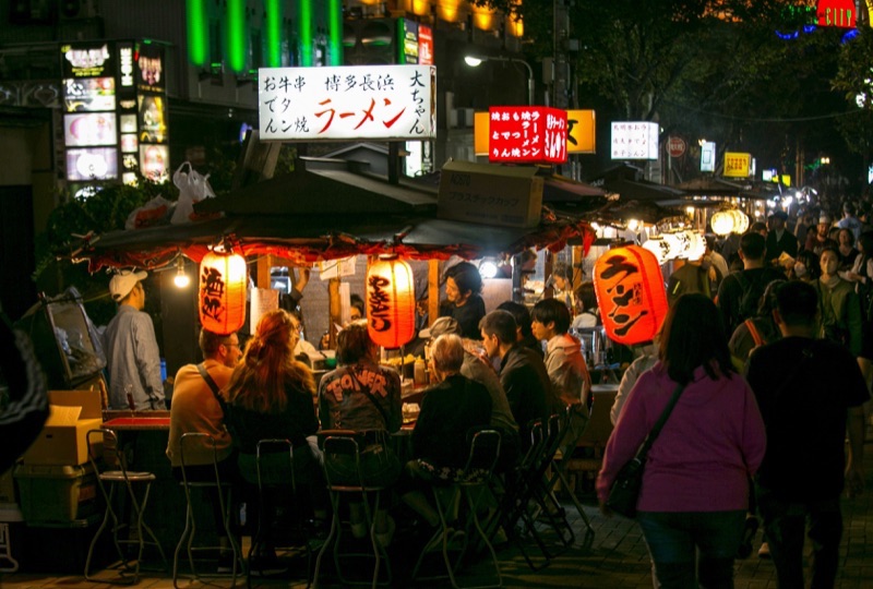 Yatai food stalls in Fukuoka at night, with people eating ramen