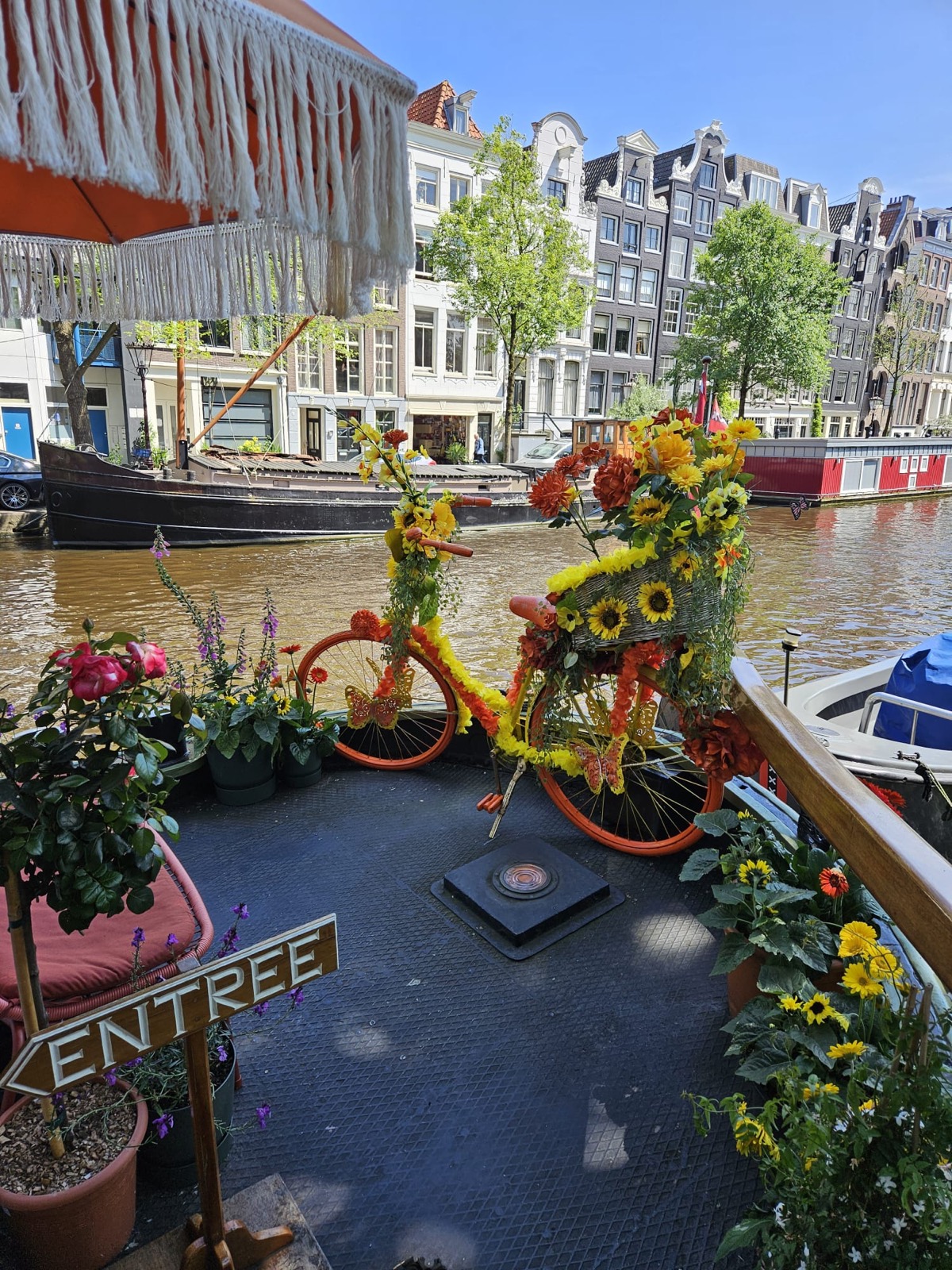 Amsterdam canal houses with a flower-covered bicycle on a bridge