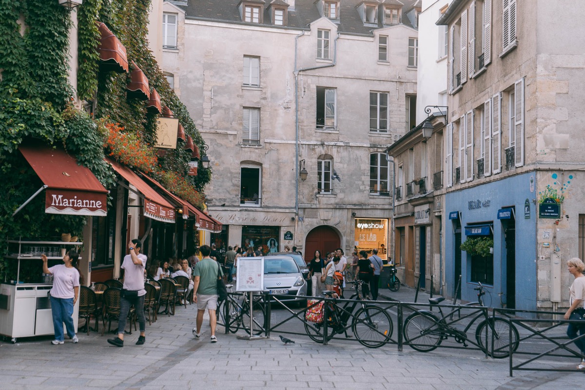 A charming street in Le Marais, Paris — cobblestones, café terraces, and Haussmann buildings
