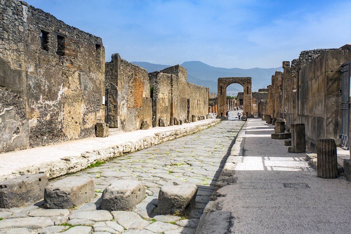 Pompeii ruins — the ancient Roman city's main street with cobblestones and columns, frozen in time by the eruption of Mount Vesuvius in 79 AD
