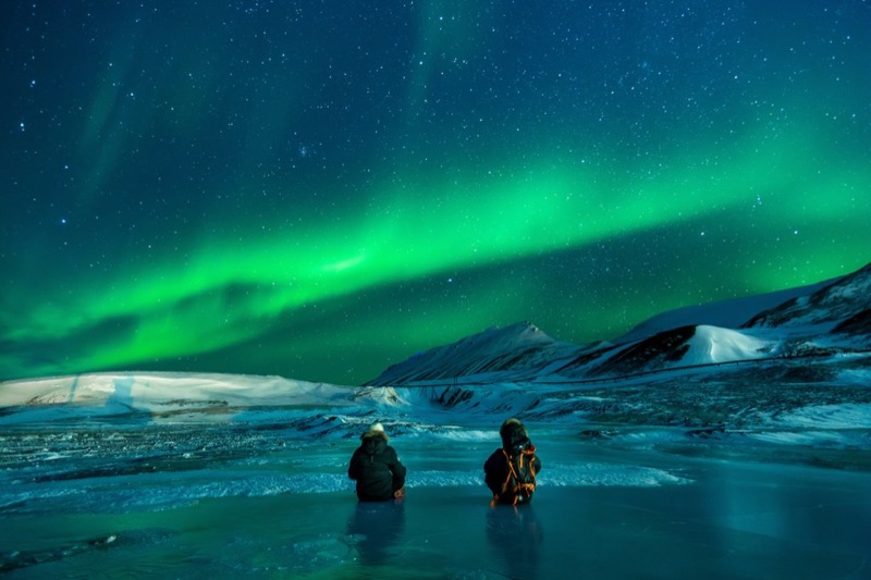 Northern Lights aurora borealis over Iceland's landscape with volcanic mountains and snow