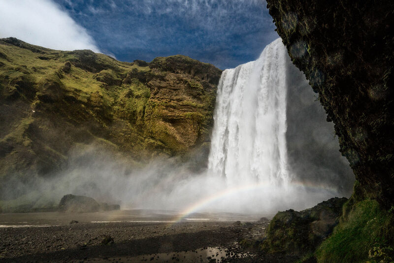Iceland Skógafoss waterfall dramatic landscape with rainbow in mist