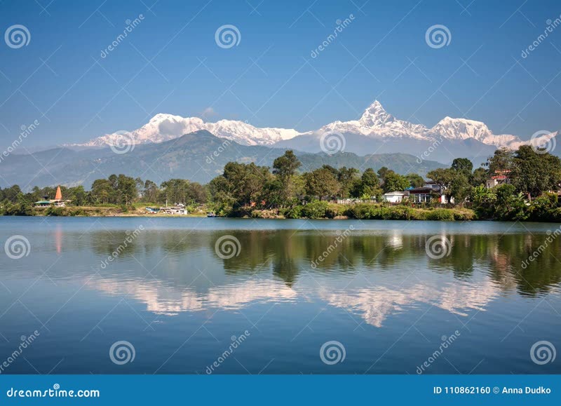 Phewa Lake in Pokhara Nepal with Annapurna mountain range reflected in the calm water at sunrise