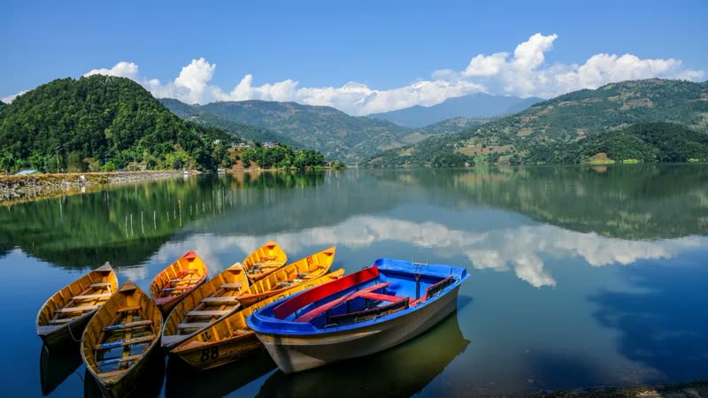 Pokhara Nepal lakeside with colorful boats on Phewa Lake and mountains in background