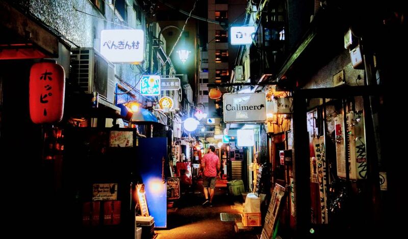 Golden Gai Shinjuku narrow alley at night with neon signs and tiny bars packed into six narrow lanes