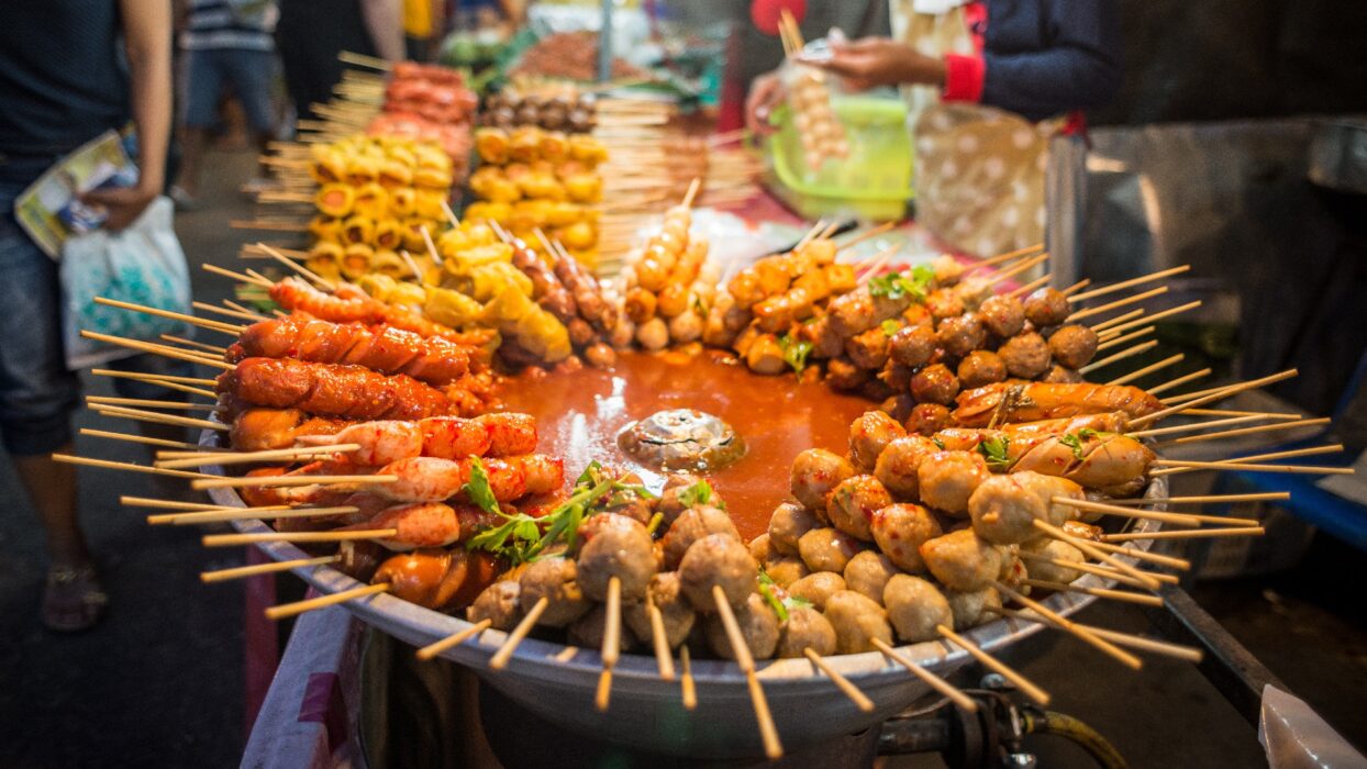 Thai street food stall in Bangkok — wok-fried noodles and grilled skewers