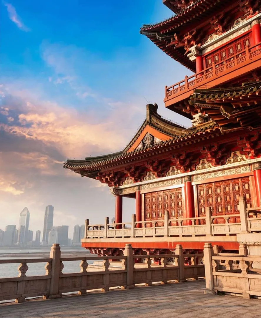 Autumn sunlight bathes the vast golden roofs and courtyards of the Forbidden City, with distant grey hutong rooftops under a clear Beijing sky.