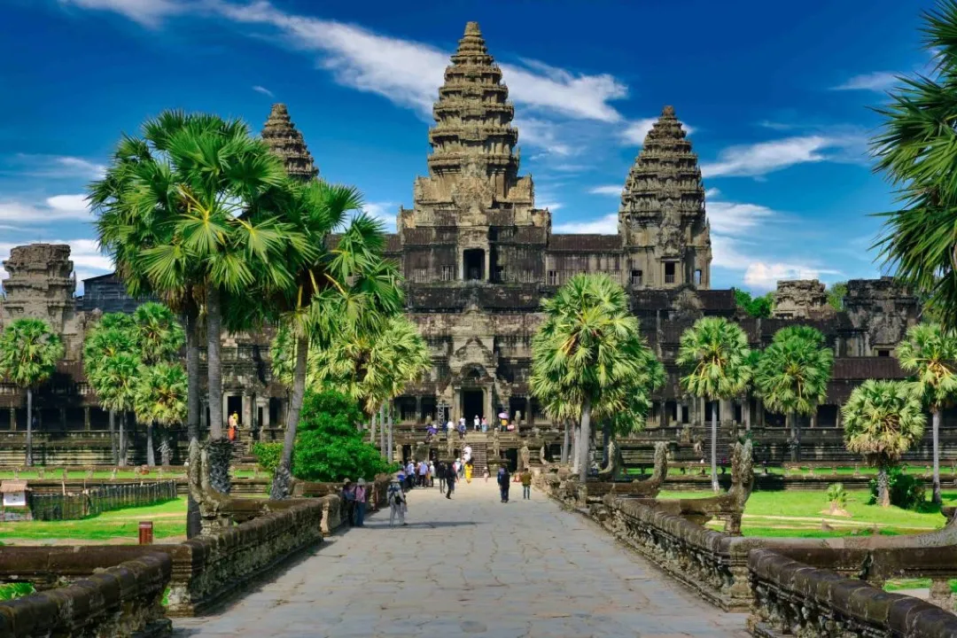 Golden sunlight bathes the ancient towers of Angkor Wat as reflections shimmer in the still lotus pond at dawn.