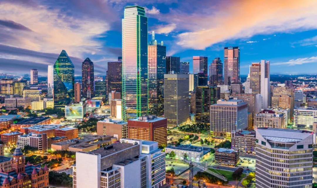 Reunion Tower's glowing orb against a vibrant downtown Dallas skyline at sunset.