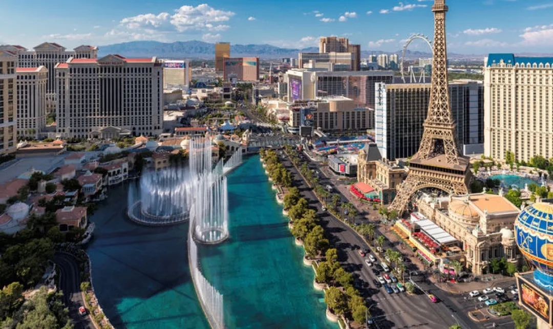 Vibrant neon lights illuminate the iconic Eiffel Tower replica and bustling Las Vegas Strip at night.