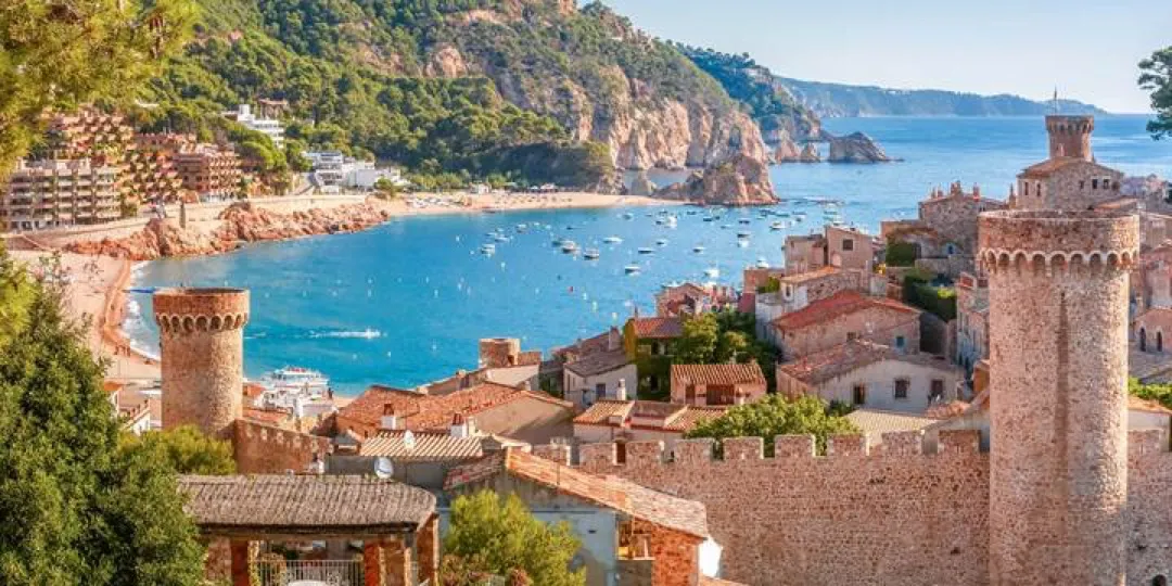 The intricate Moorish architecture of Granada's Alhambra Palace glows golden at sunset, reflecting in tranquil pools with the Sierra Nevada mountains in the background.