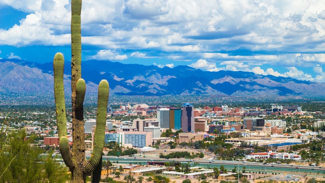 Historic adobe buildings in Tucson's Barrio Viejo under a clear blue sky, with distant mountains framing the scene.