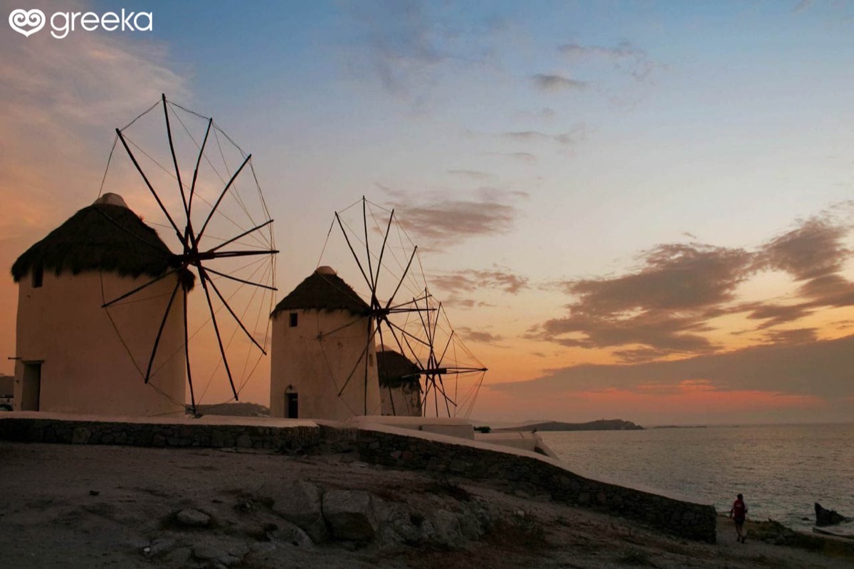 Mykonos windmills silhouetted against a dramatic sunset sky