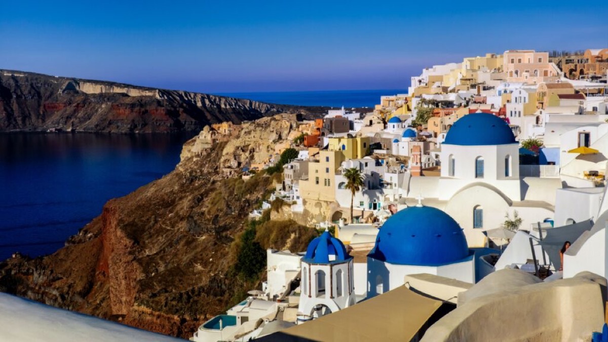 Santorini caldera view with blue domes and cascading white village at golden hour