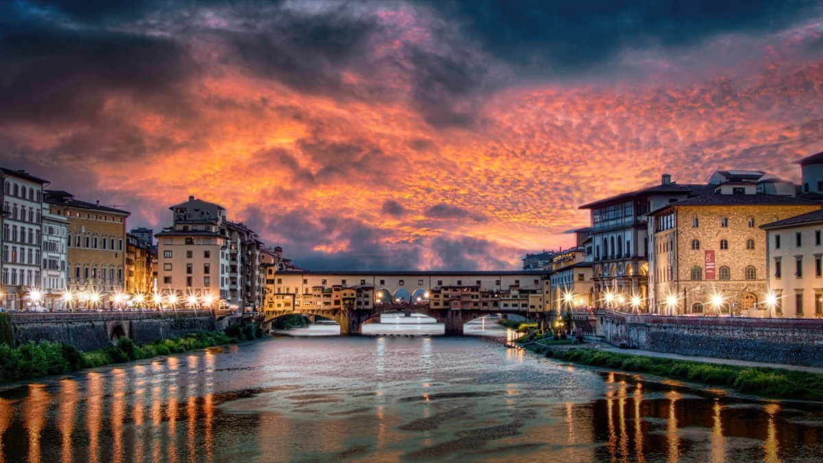 Ponte Vecchio bridge reflected in the Arno River at sunset in Florence