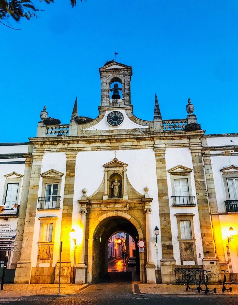 Arco da Vila city gate in Faro Old Town at blue hour with warm lantern glow, Algarve