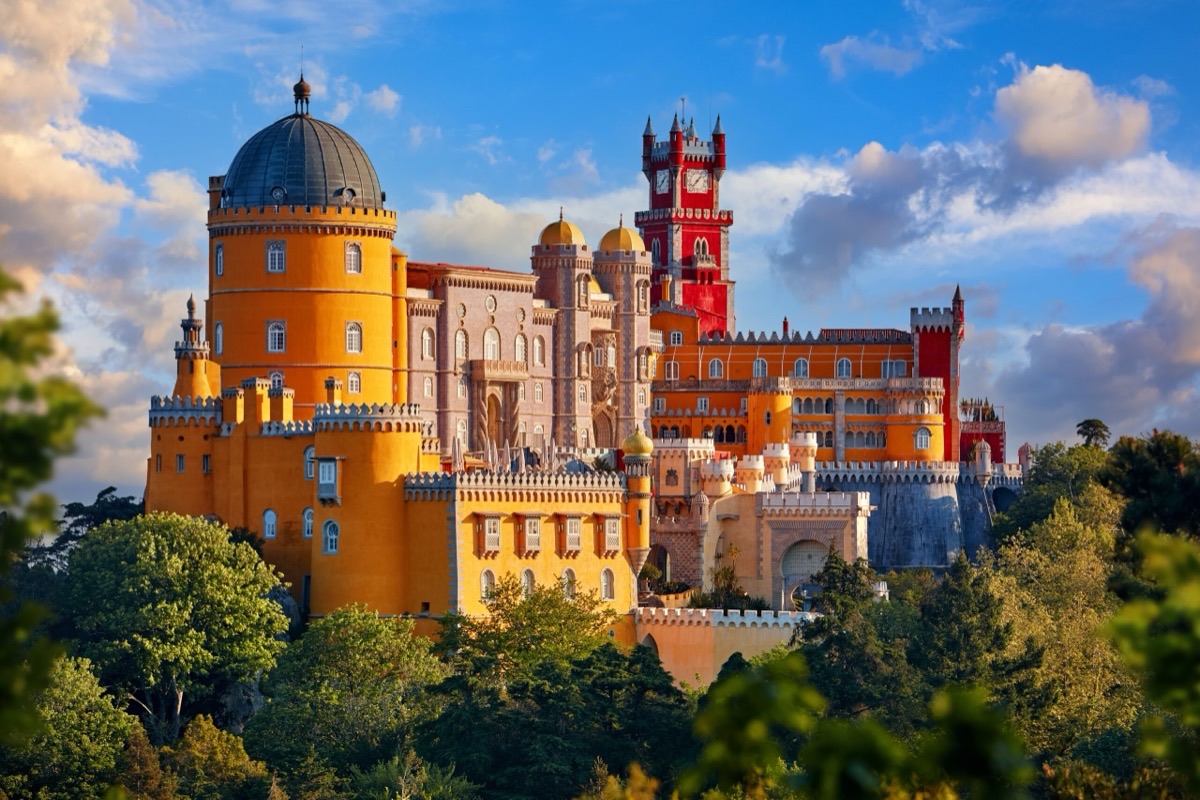 Pena Palace Sintra in golden-hour light with colorful yellow and red facades above lush greenery