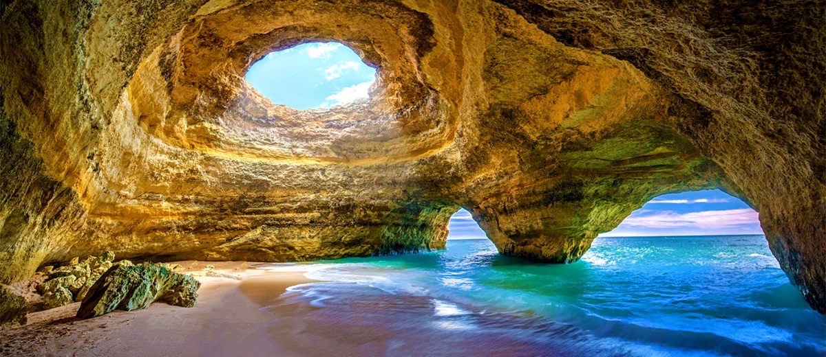 Benagil Cave interior with iconic oculus skylight, golden walls, and turquoise sea, Algarve
