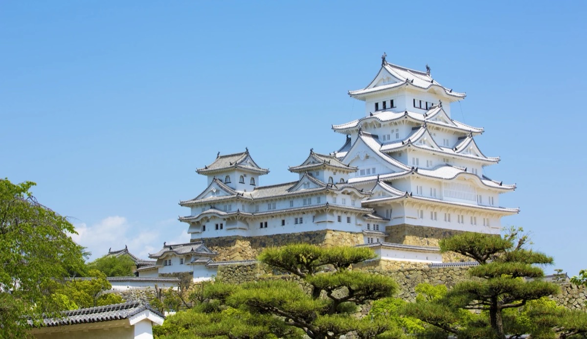 Himeji Castle framed by cherry blossoms with red bridge reflection in Japan