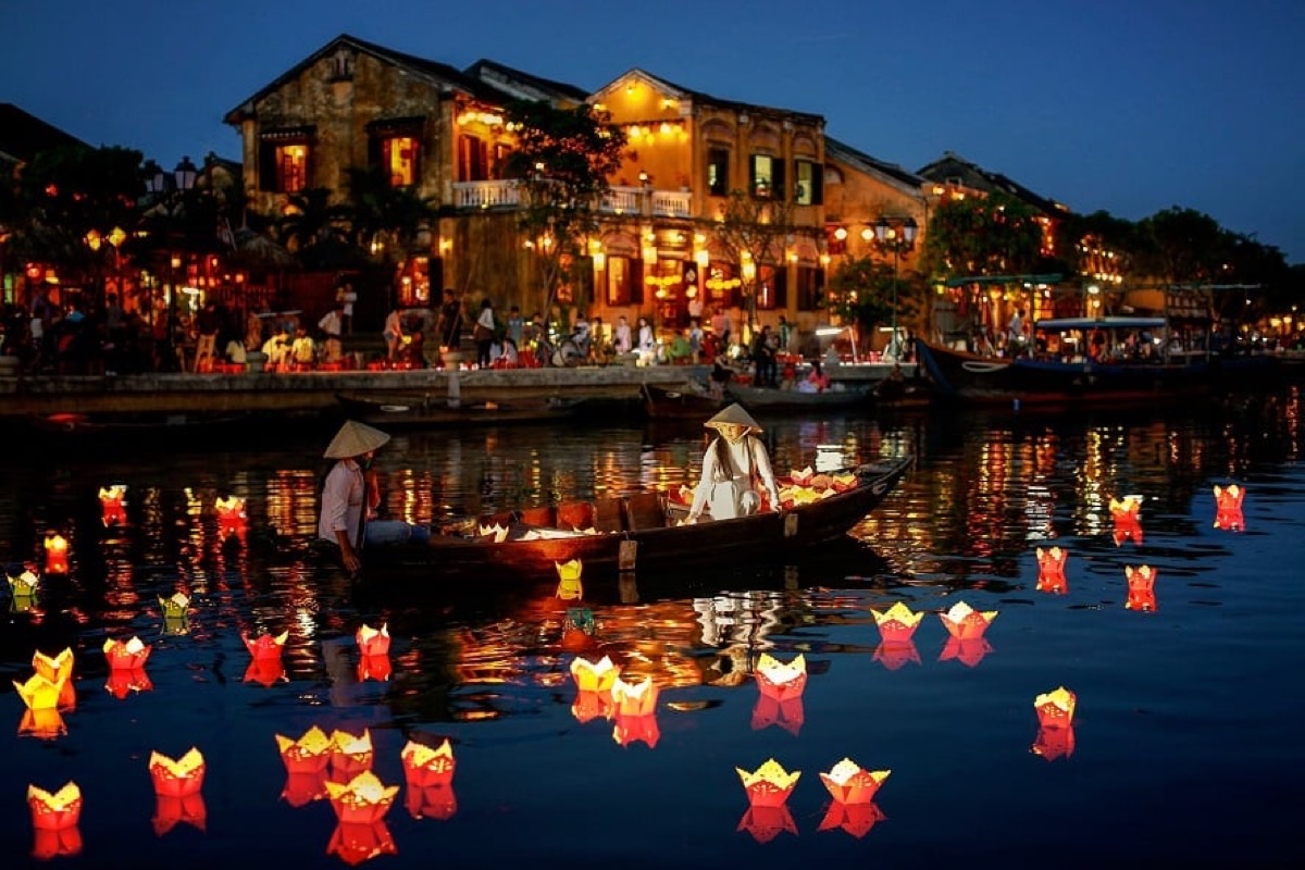 Colorful paper lanterns floating on the Thu Bon River at blue hour in Hoi An Ancient Town