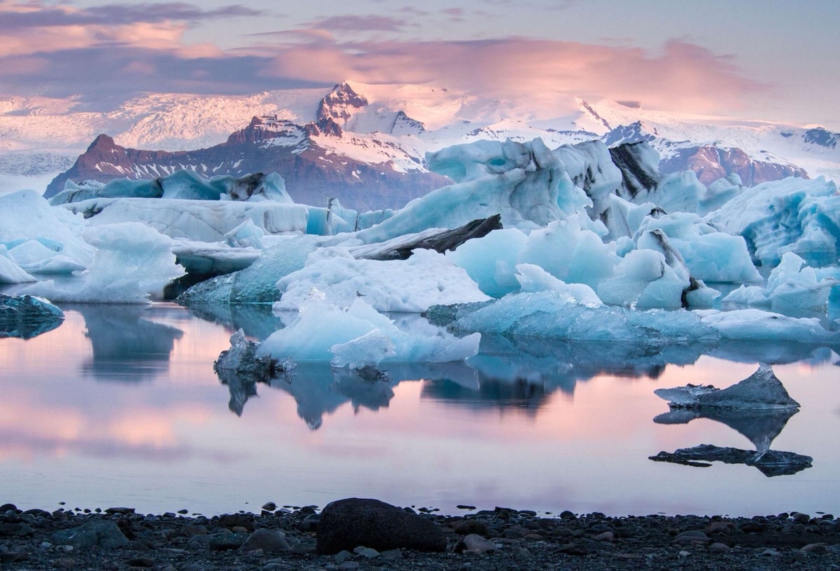 Jokulsarlon glacier lagoon at sunset with blue icebergs reflecting in still water, Iceland