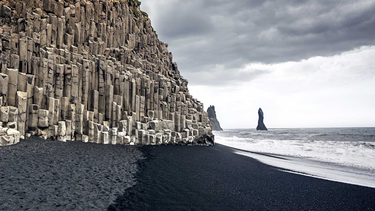 Reynisfjara black sand beach with towering basalt columns, crashing waves, and sea stacks, Iceland