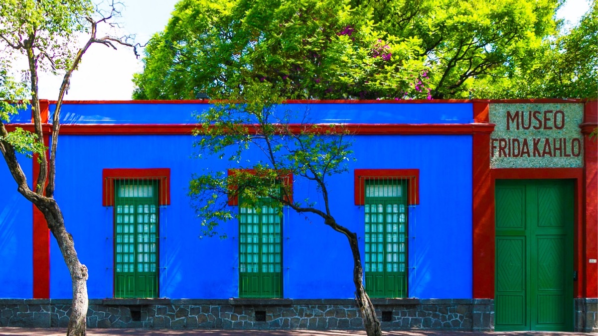 Vibrant cobalt blue facade of Casa Azul Frida Kahlo Museum with red trim and green doors in Coyoacan