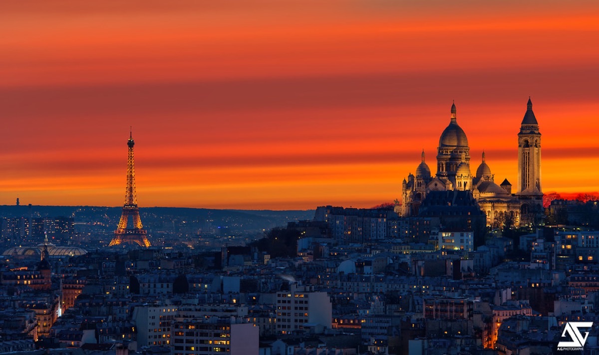 Sacré-Cœur Basilica and Eiffel Tower illuminated under a blazing Paris sunset sky