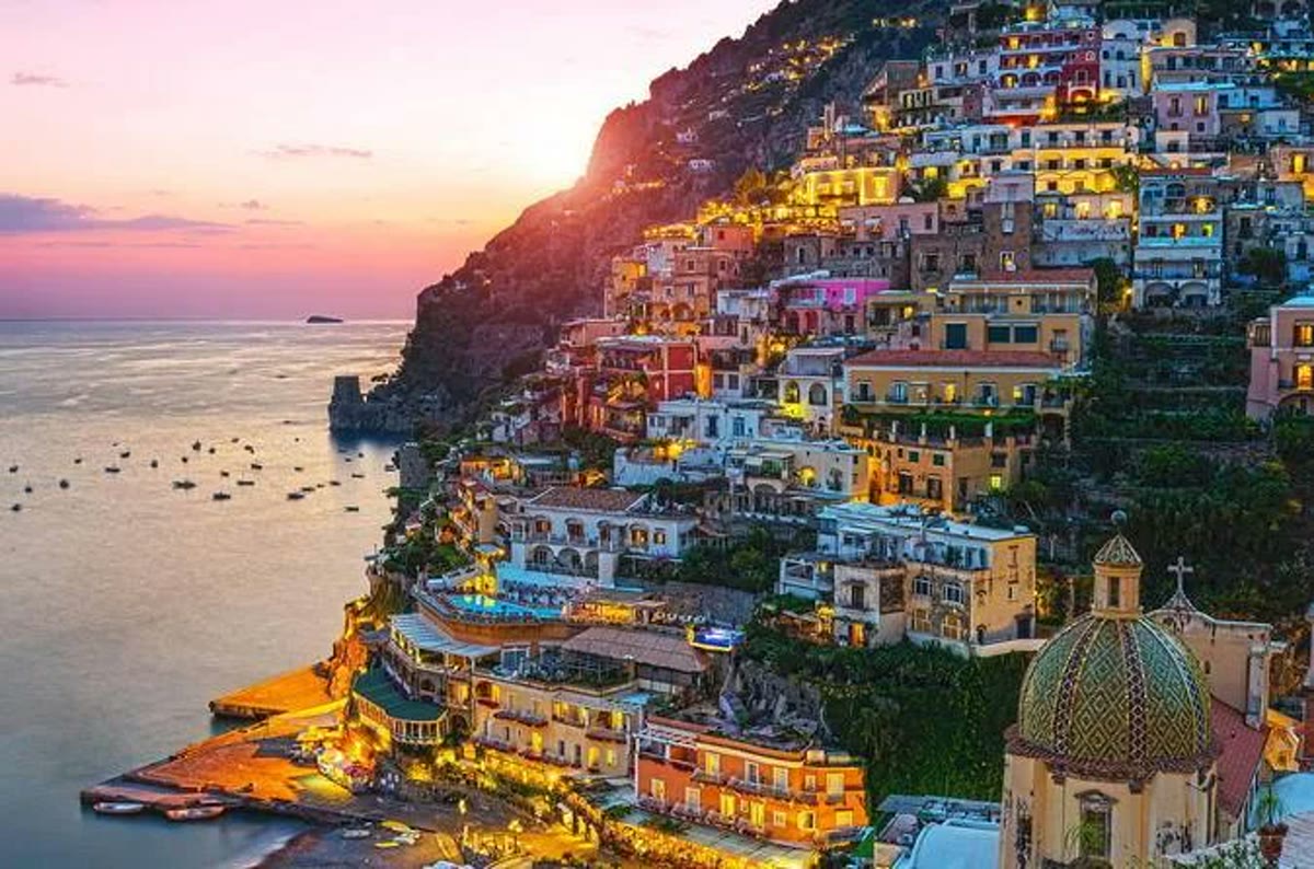 Positano colorful houses cascading down the cliffside to the sea at sunset, Amalfi Coast